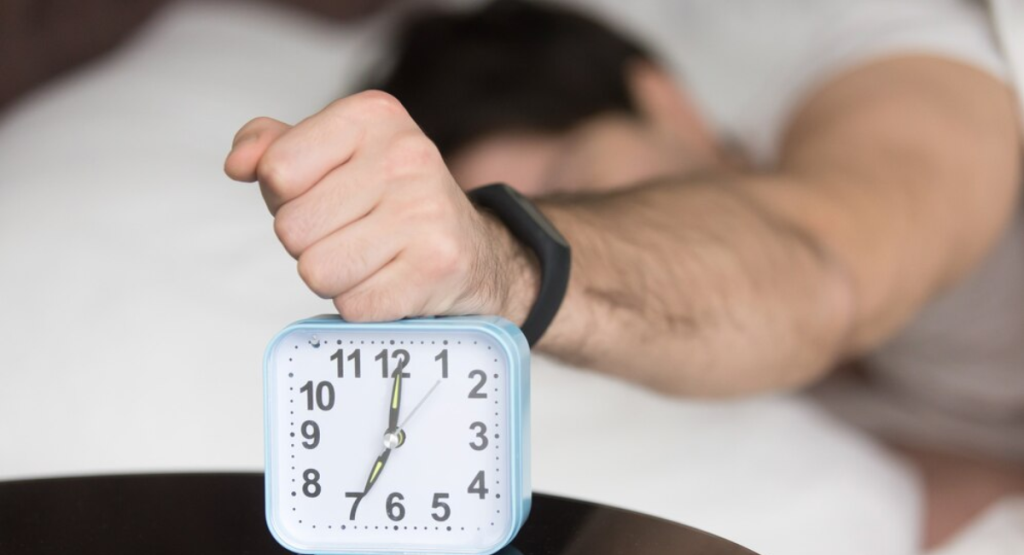 A frustrated man slamming his fist on an alarm clock after a sleepless night, highlighting the need for expert insomnia treatment in Mohali